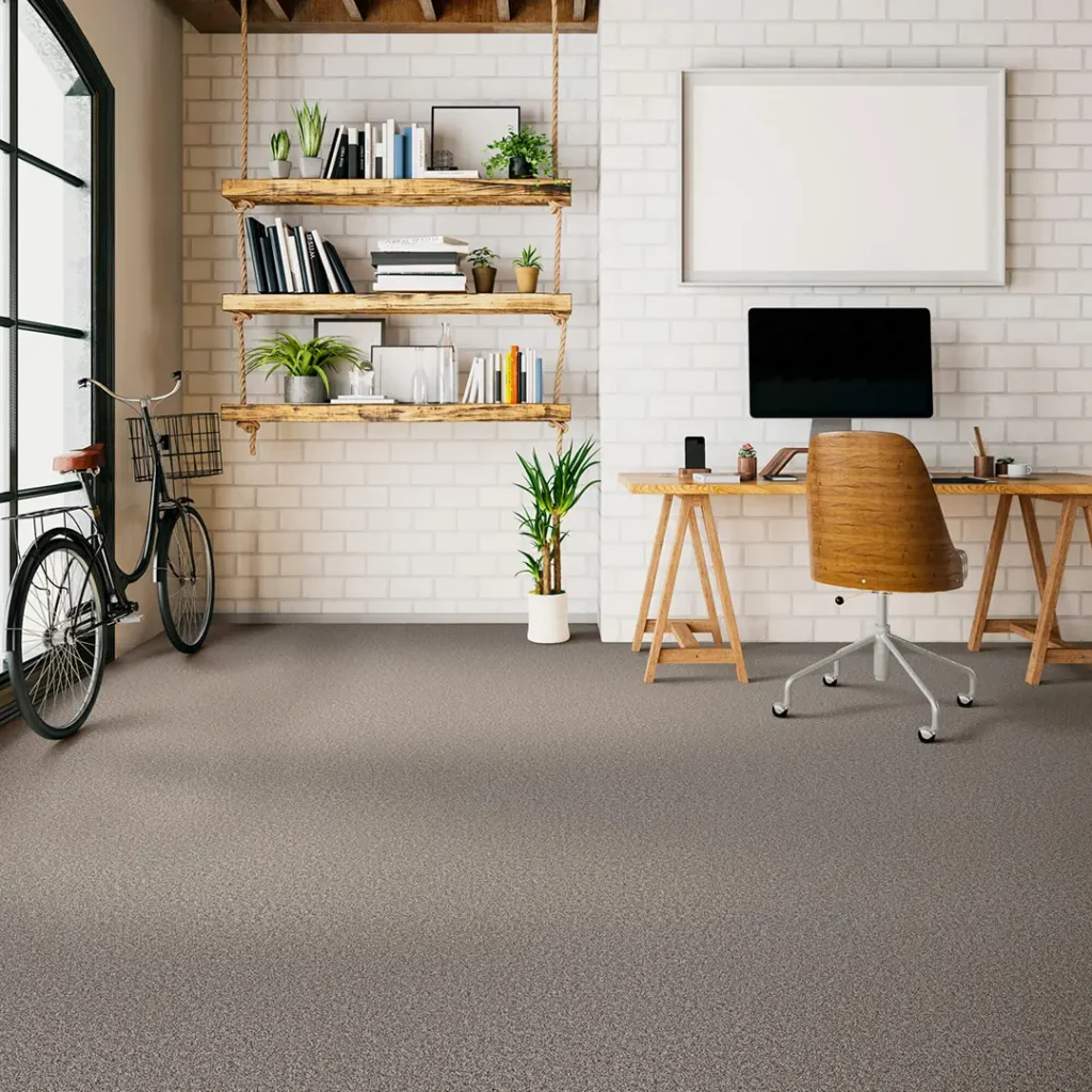 Textured charcoal-grey low-pile carpet in a chic home office with a white painted brick wall, wooden desk, and a vintage bicycle.