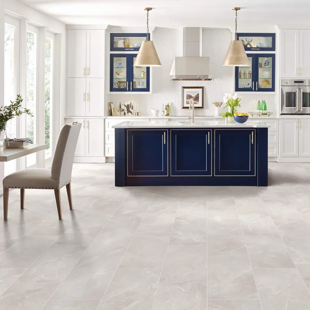 Large, light grey marble-textured floor tiles in a luxury white kitchen centered around a prominent navy blue island.