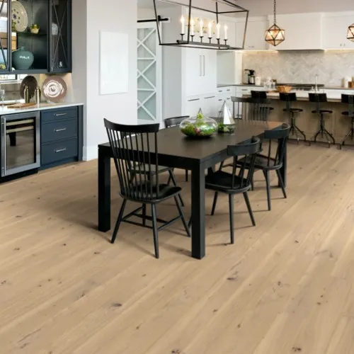 Light-toned natural hardwood flooring in a modern, open-concept dining and kitchen space, featuring a black dining table with matching chairs under a contemporary linear chandelier.
